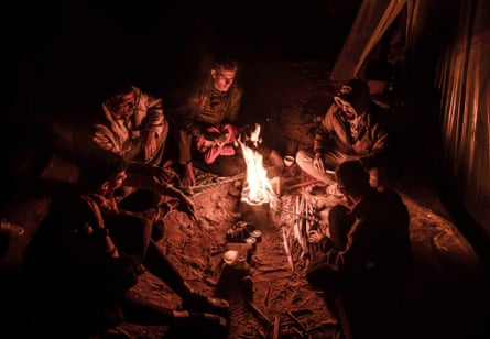 Palestinians in Rafah huddle round a fire to keep warm on New Year’s Eve after being forced from their homes by Israeli airstrikes.