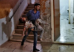 A Syrian man carries a severely-wounded boy at a makeshift hospital in the rebel-held town of Douma