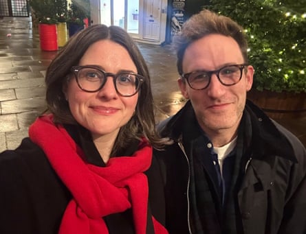 Woman and man on a blind date - woman in red scarf and dark coat, man in dark coat. Both with glasses. Christmas tree behind them
