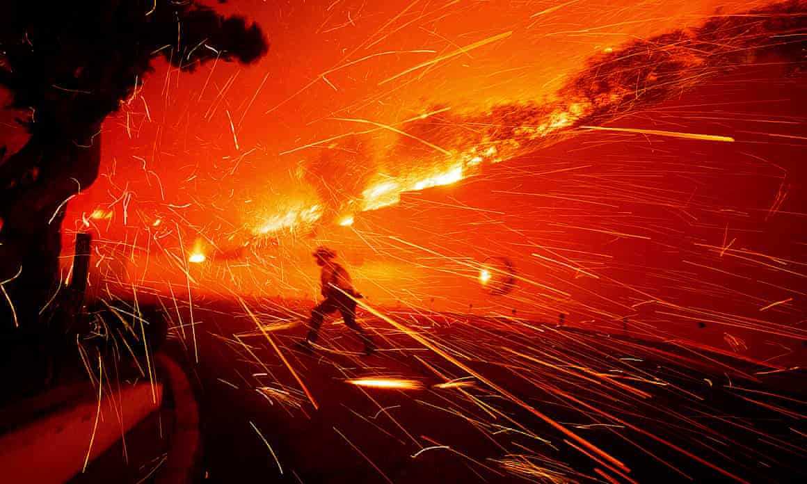 A figure runs amid sparks, flames and smoke
