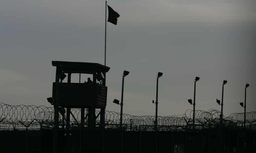 A US military guard keeps watch from a tower overlooking the perimeter of Camp Delta detention center at Guantanamo Bay in June 2006.