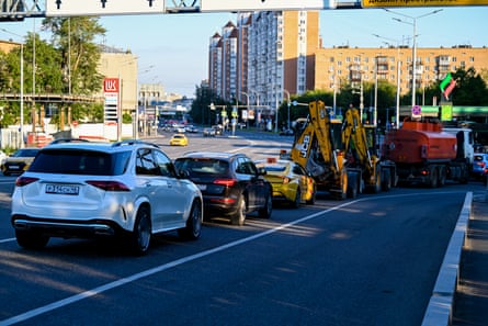 Cars and construction vehicles parked on the street trying to get into a petrol station