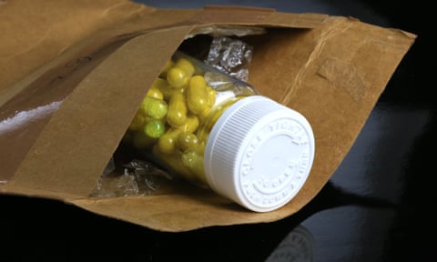 a bottle of yellow pills in a padded mailorder bag