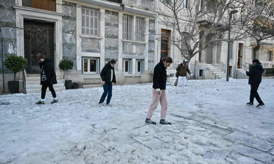 Οι άνθρωποι στο κέντρο της Αθήνας προσπαθούν να περπατήσουν στο χιόνι.