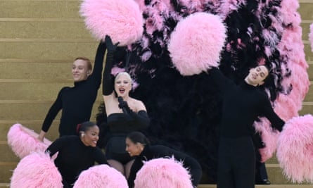 Lady Gaga on steps next to the Seine surrounded by dancers with pink pompoms