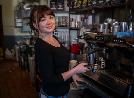 A barista smiles whilst at the espresso coffee machine.