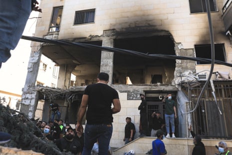 People gather below the building with its walls blown out.
