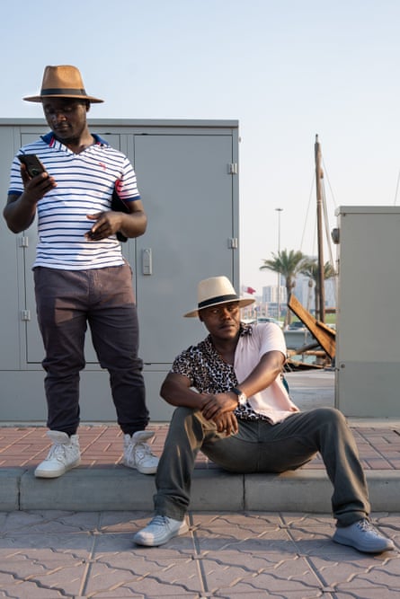 کندی، یک راننده، و لوئیز، یک کارگر ساختمانی از کنیا در حال استراحت در کنار دریا در دوحه، قطر در یک روز آفتابی.