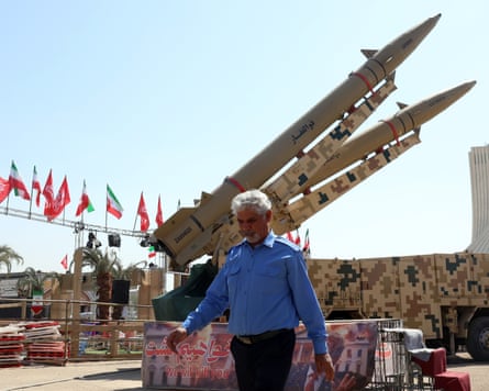 An Iranian security officer walks past missiles on display in central Tehran