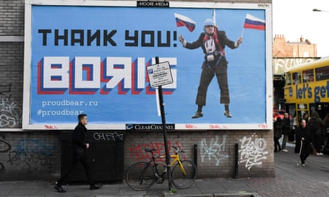 Man walks past a billboard depicting Boris Johnson waving Russian national flags reading 'Thank you Boris'.
