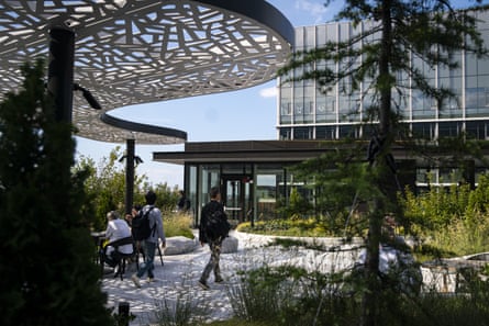 A person walking on a company’s campus with greenery.