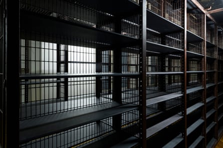 An installation view of Enemies and Rascals at the Maughan Library.Empty bookshelves. Darkened room.