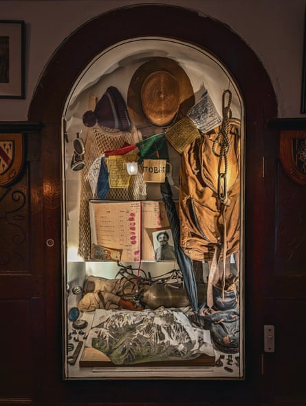 Climbing equipment, a logbook and a photo of Tenzing behind glass in a panelled room