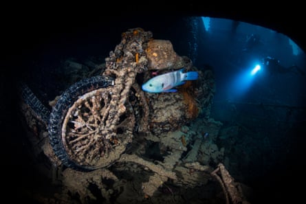 Divers explore a rusted motorbike inside the wreck of SS Thistlegorm in the Red Sea.