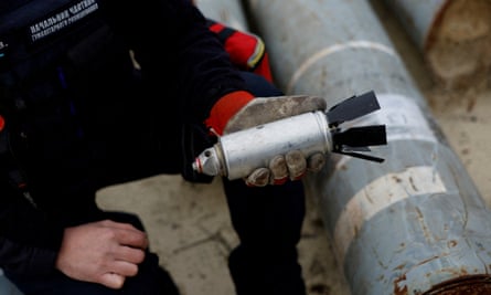 A Ukrainian soldier holds a defused cluster bomb from an MSLR missile used by the Russian army, in the region of Kharkiv, Ukraine