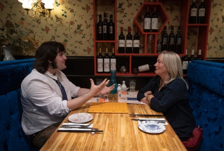 Lucas and Marie-Rose sitting opposite one another chatting at a restaurant table