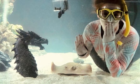 Woman wearing snorkel in a fish tank with stingray and seahorse