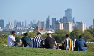 People enjoy the sunshine on Primrose Hill, London.