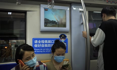 Commuters wearing face masks ride on a subway train as a TV screen showing China’s CCTV reporting news of military conducting missiles launch exercises, in Beijing, Thursday, Aug. 4, 2022.