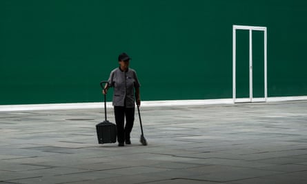A cleaner walks by a vacant shop at an outdoor shopping mall in Beijing.