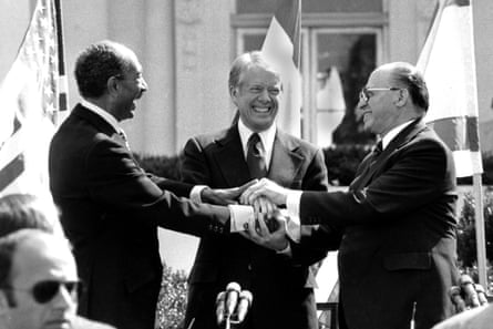 three men smile as they clasp hands