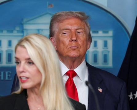 President Trump looking to the side while standing behind a female member of his press team
