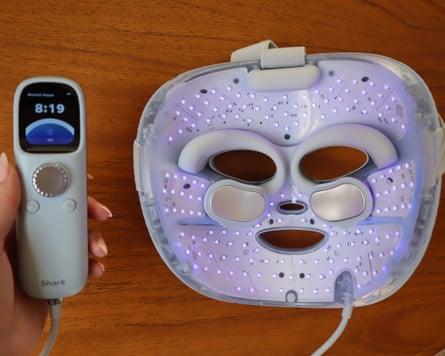 Controller unit and Shark Cyroglow LED face mask on a wooden countertop.
