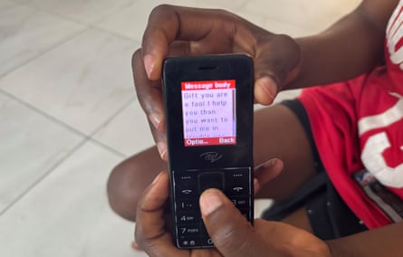 A small mobile phone, with a message on the screen that reads ‘Gift you are a fool I help you then you want to put me in trouble you’