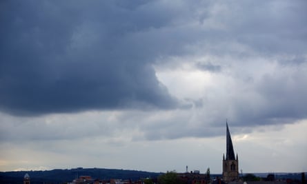 photo showing overview of town with the twisted church spire silhouetted against a vast expanse of dark grey, cloudy sky