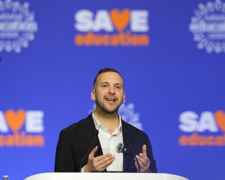 Zack Polanski speaks on stage in front of branding, saying ‘save education’