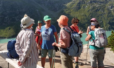 Un grupo de mujeres vestidas con equipo de senderismo cerca de un lago en las montañas