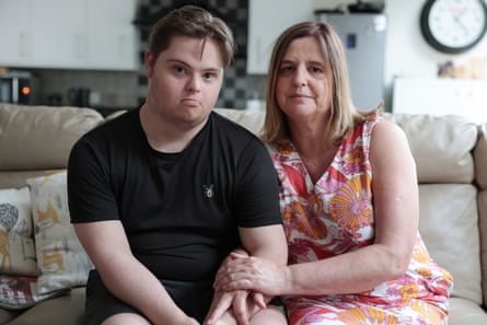 Carer Elizabeth Tait and her son, Oliver, sit together on a sofa, holding hands