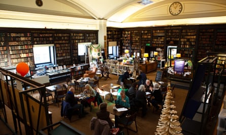 İnsanlar Manchester'daki Portico kütüphanesindeki masalarda oturup yemek yiyor ve konuşuyorlar