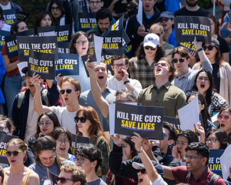 people hold signs that say 'kill the cuts save lives'