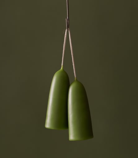 Two green candles hanging from a string on a green background