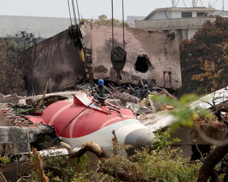 A worker searches the wreckage of the Air India Boeing plane