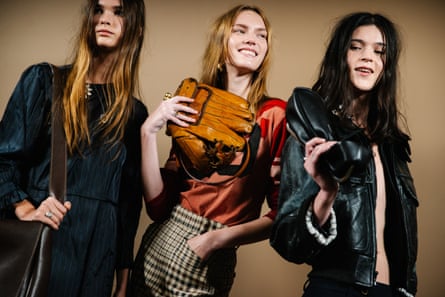 Three women in fashionable clothes, one holding up an old baseball glove