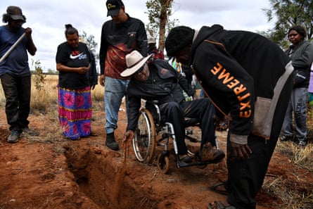 Uluru traditional owner Reggie Uluru drops soil into Yukun’s grave.