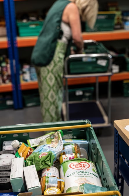 A woman in a food bank with a basket of goods in the foreground
