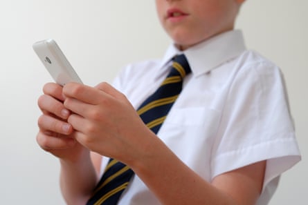 A boy in school uniform using a smartphone