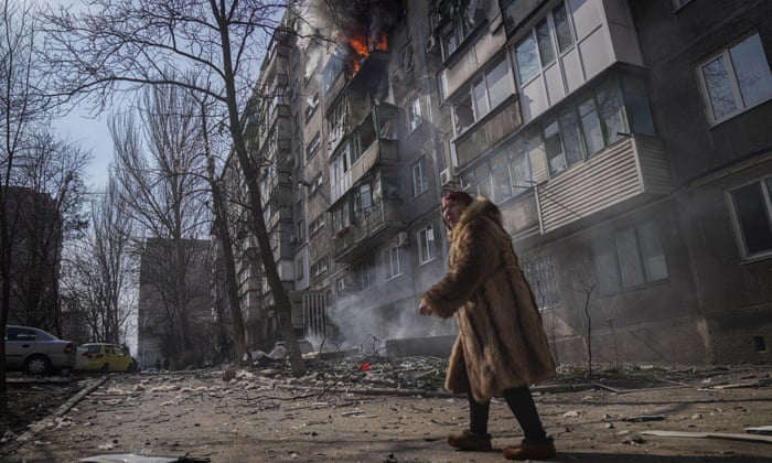 A woman walks past a burning apartment building after March shelling in Mariupol, Ukraine, in one of Evgeniy Maloletka’s photos