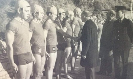 Black and white pic of lineup of lifeguards with man in coat shaking hands with one