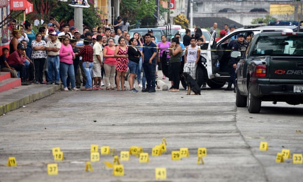 People stand near bullet casings at a crime scene after a shootout in Veracruz. Mexico is grappling with a record murder rate.