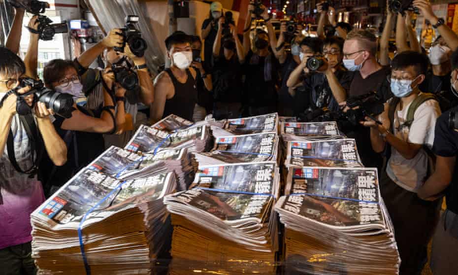 Photographers gather round as workers deliver the final Apple Daily newspapers into newsstands in Hong Kong
