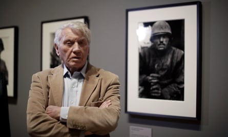 Don McCullin in 2019, next to his 1968 photograph of a US marine in Vietnam.
