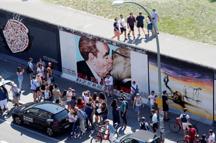 Tourists are seen in front of graffiti depicting former Soviet leader Leonid Brezhnev kissing his East German counterpart Erich Honecker along the East Side Gallery.