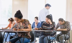 Professor watching college students taking test in classroom<br>GettyImages-683735779