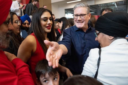 Starmer reaching out to shake someone’s hand from within a crowd of people