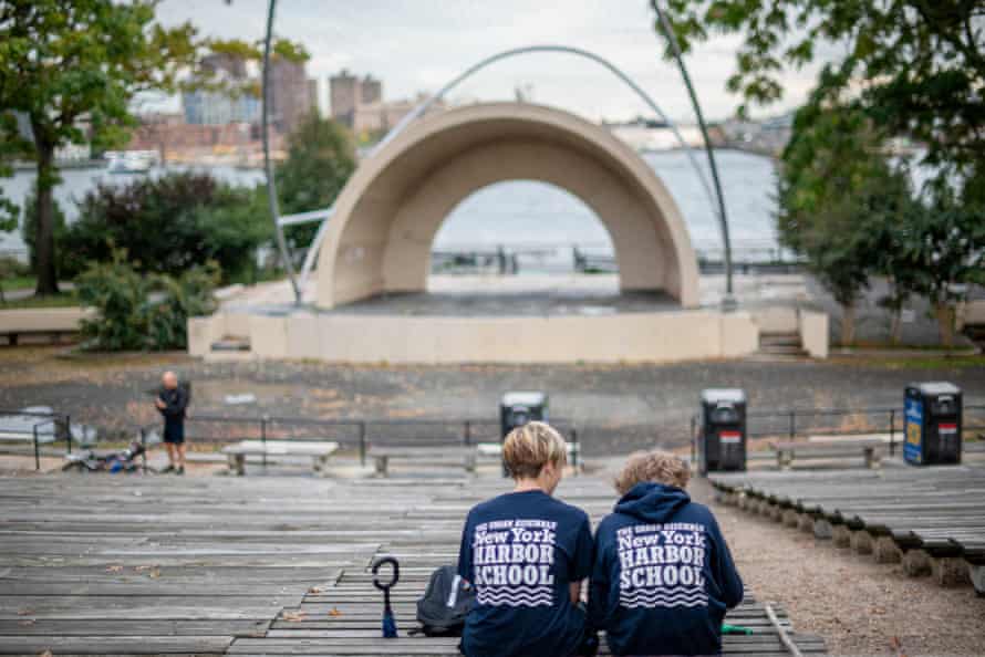 Two schoolchildren sit in the East River Amphitheater in the East River Park.