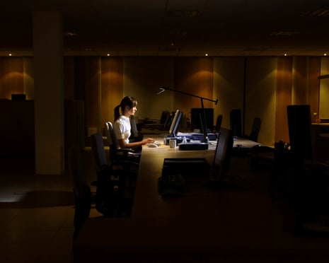 Side view of a young woman working on computer in dark office